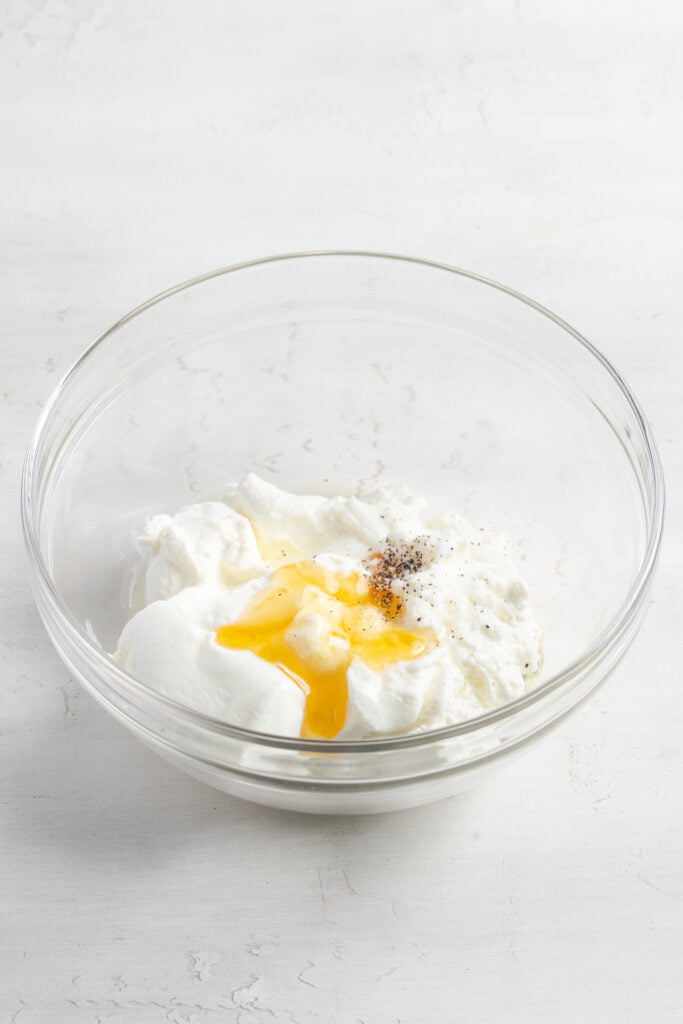 ingredients for whipped ricotta added to a clear mixing bowl.