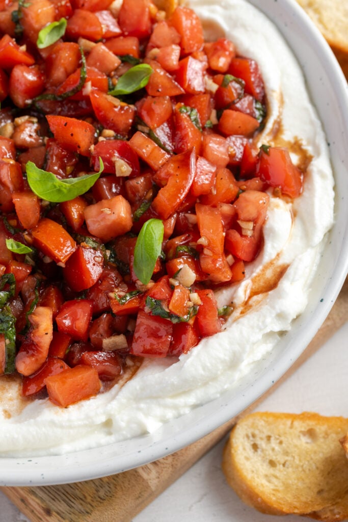 closeup shot of whipped ricotta topped with bruschetta dip.