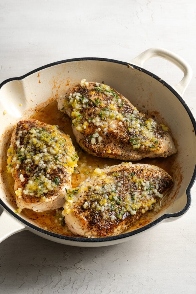baked lemon pepper chicken in a pan after pouring on the lemon pepper seasoning mixture.