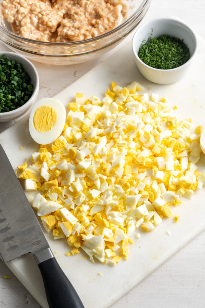 finely chopped hard boiled eggs on a white cutting board.