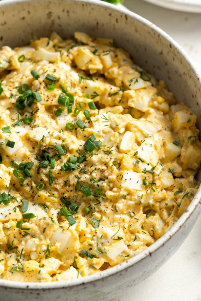 closeup shot of cottage cheese egg salad in a serving bowl topped with fresh herbs as garnish.