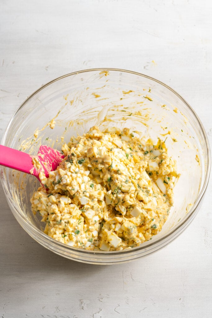 cottage cheese egg salad in a mixing bowl after stirring together with a pink silicone spatula.