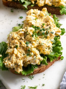 healthy egg salad with cottage cheese served on multigrain toast with a lettuce leaf and topped with fresh chives and dill.