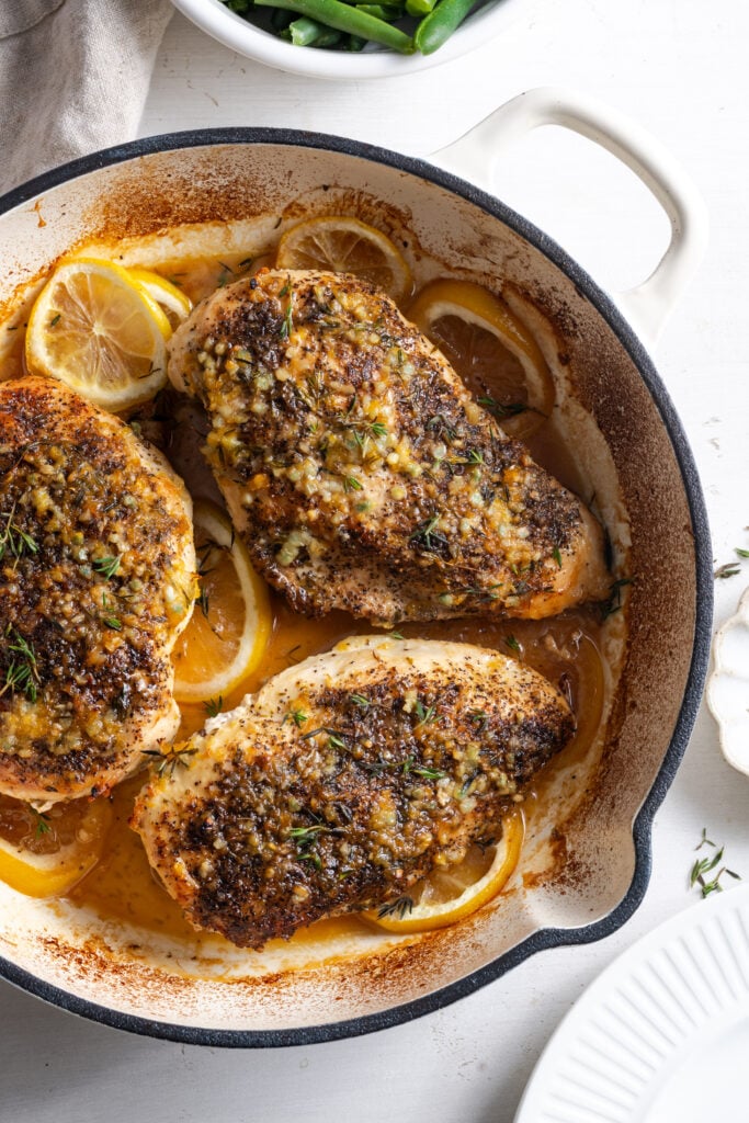 overhead shot of lemon pepper chicken breasts in a dutch oven after baking.