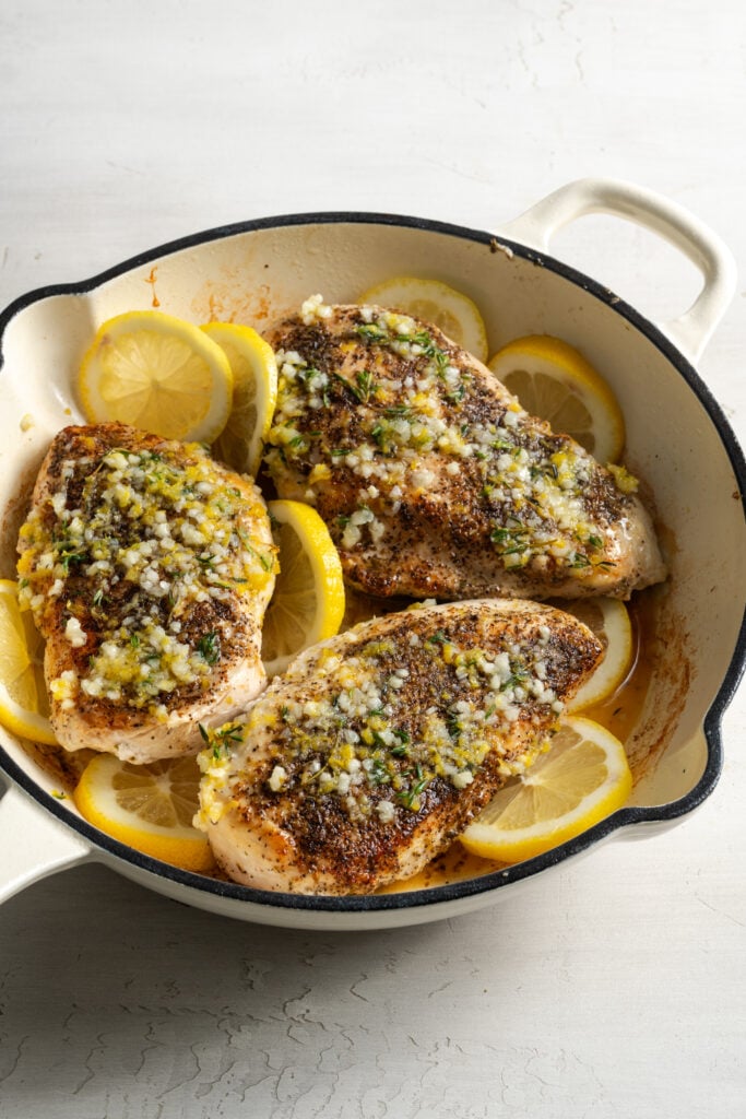browned lemon pepper chicken breasts in the skillet after tucking in thin slices of lemons.