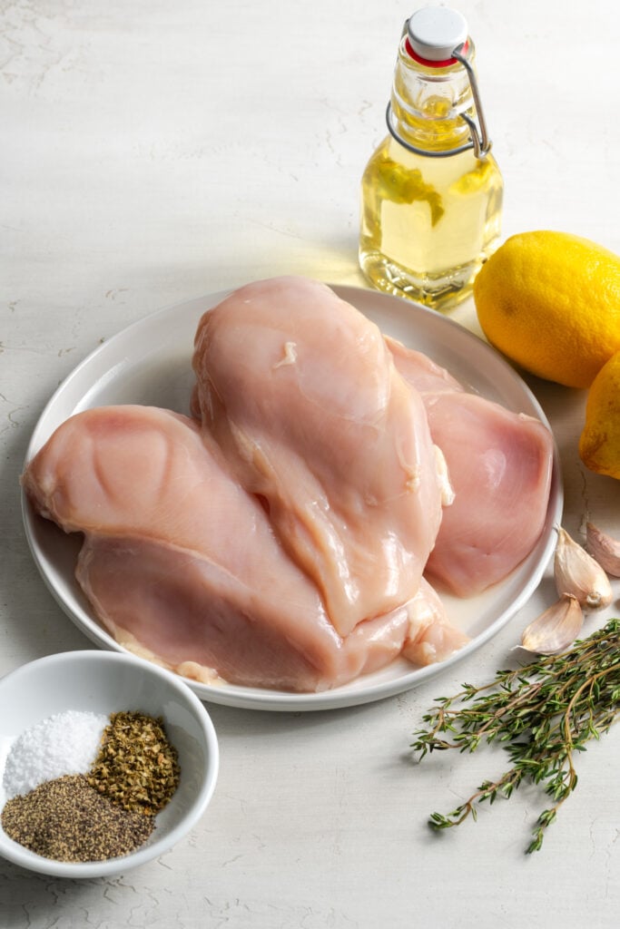 ingredients needed to make lemon pepper baked chicken measured out on a white table.