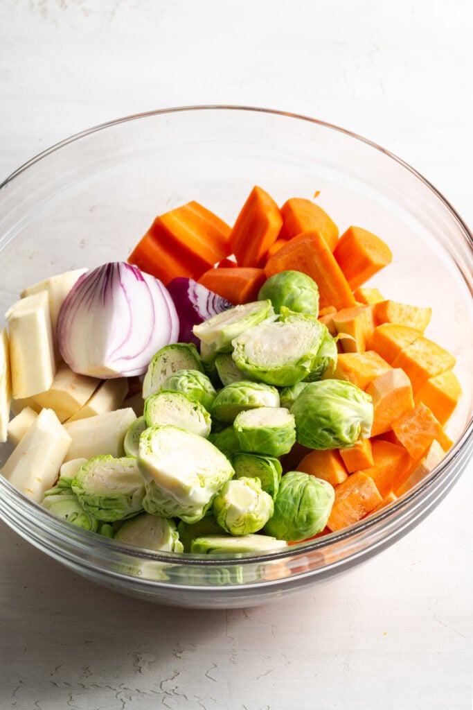 chopped fall vegetables in a mixing bowl before tossing with seasoning and glaze.