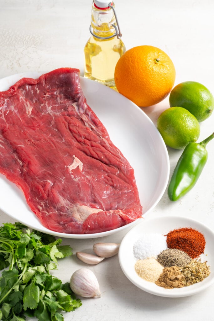 marinated flank steak taco ingredients measured out on a white table.
