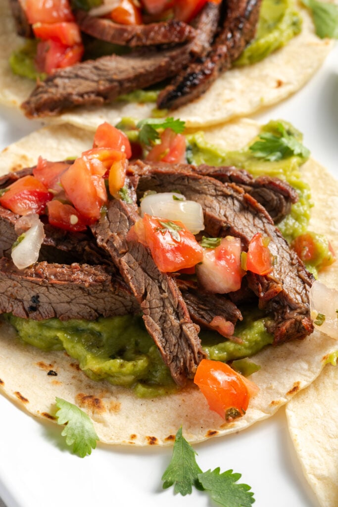 marinated flank steak tacos with avocado mash and pico de gallo.