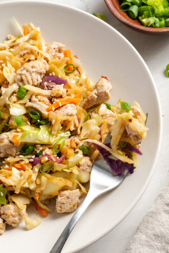 closeup shot of a plate of turkey egg roll in a bowl with a silver fork taking a bite.