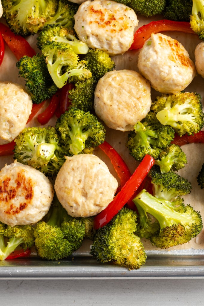 closeup shot of baked teriyaki chicken meatballs and veggies on the sheet pan before glazing with the pineapple teriyaki sauce.