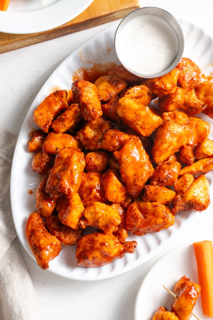 air fried buffalo chicken breast bites on a white serving platter with ranch dressing.