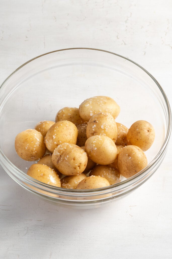 raw baby potatoes in a mixing bowl with oil and salt.