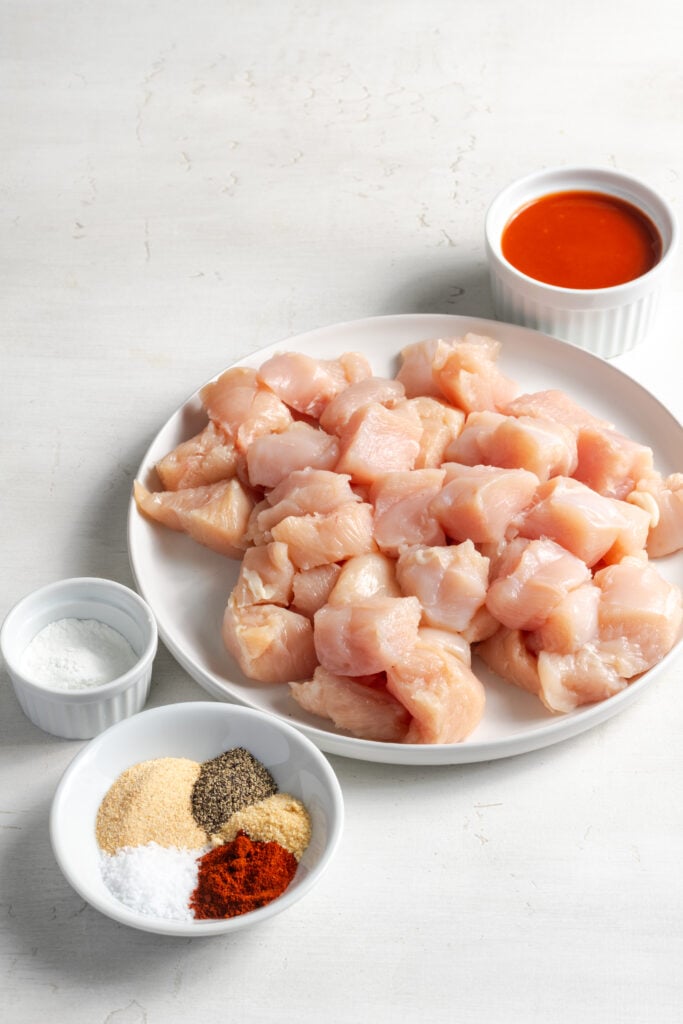 ingredients for making air fryer buffalo chicken bites recipe measured out on a white table.