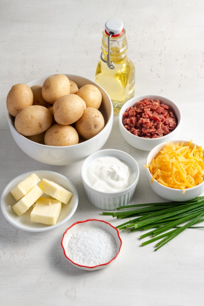 ingredients for making loaded twice baked mini potatoes recipe measured out on a white table.