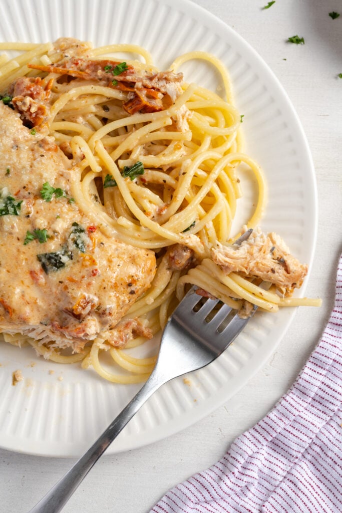 silver fork with a twirl of spaghetti and a bite of slow cooker chicken.
