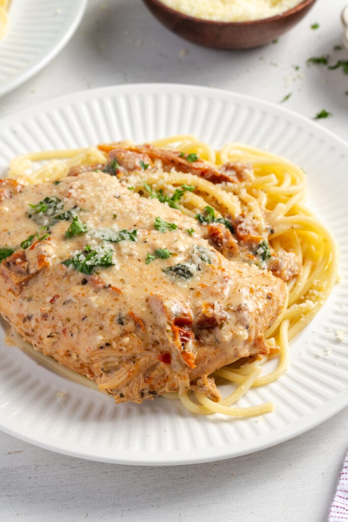 plated tuscan chicken crockpot dinner on a bed of spaghetti.