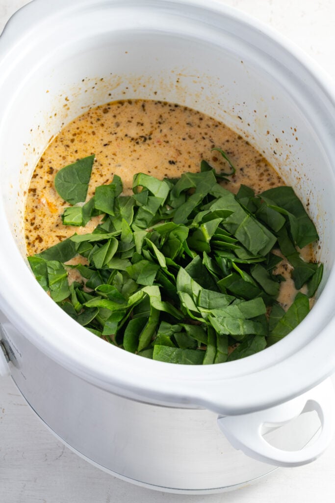 ribbons of fresh spinach added to the cooked chicken and sauce in the slow cooker.