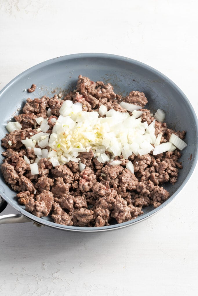 onions and garlic added to the pan with the browned ground beef.