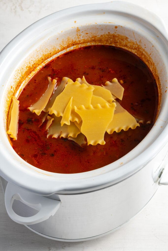 broken lasagna noodles added to the soup base in the slow cooker.