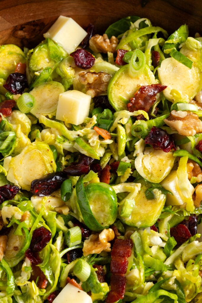 closeup shot on the tossed shaved brussels sprouts salad in a wooden bowl.
