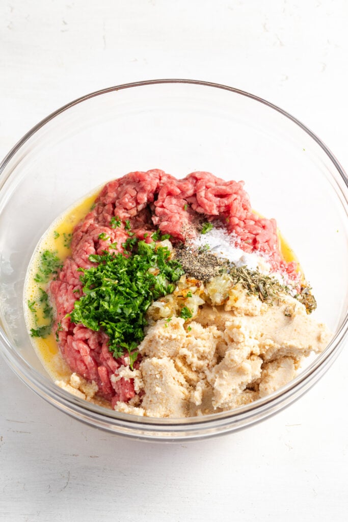 mixing bowl filled with the french onion meatball ingredients before mixing.