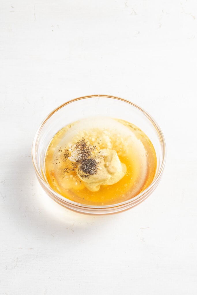 brussels sprouts salad dressing ingredients added to a small clear mixing bowl.