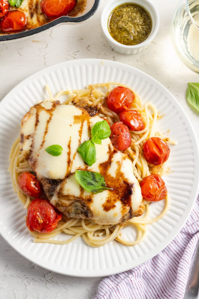 plated skillet caprese chicken on a bed of noodles.