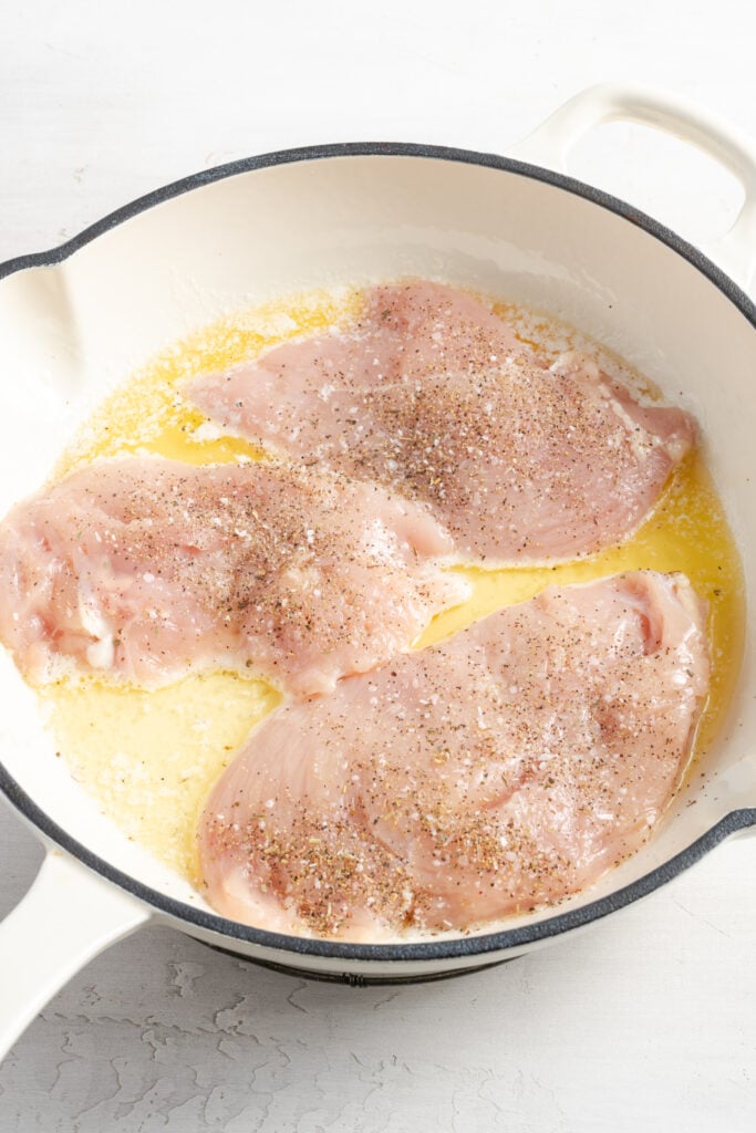chicken breasts added to a skillet with oil.