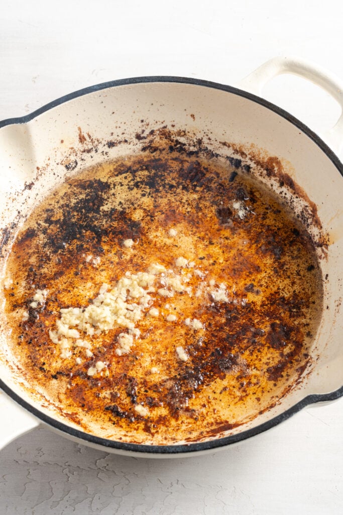 garlic cooking in the oil and fond after the chicken was removed from the skillet.