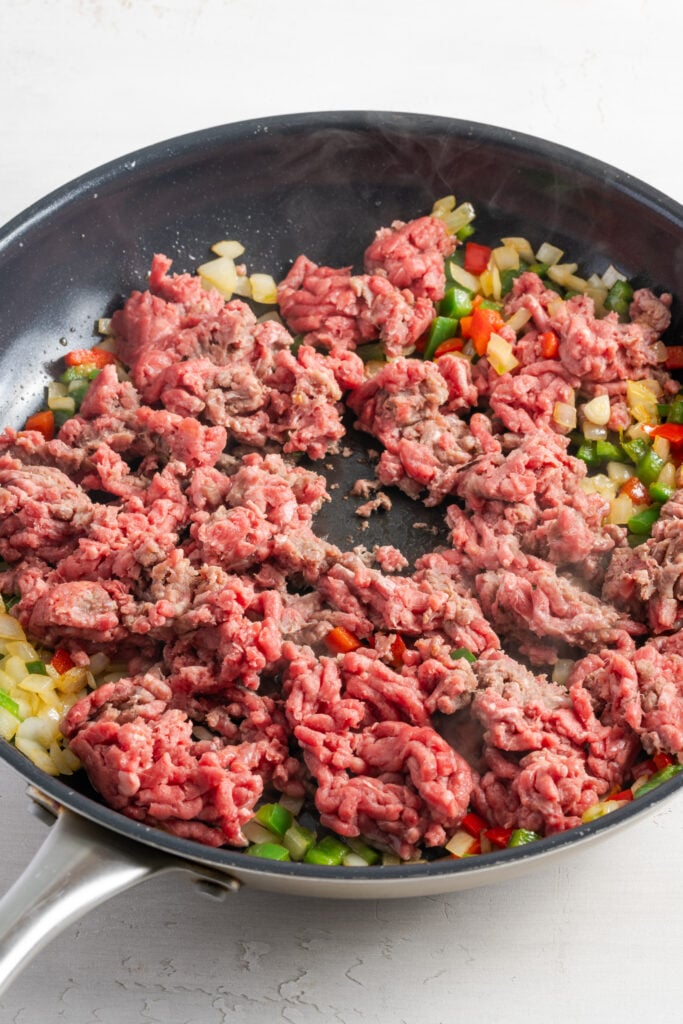 ground beef added to the skillet with the sauteed onion and peppers.