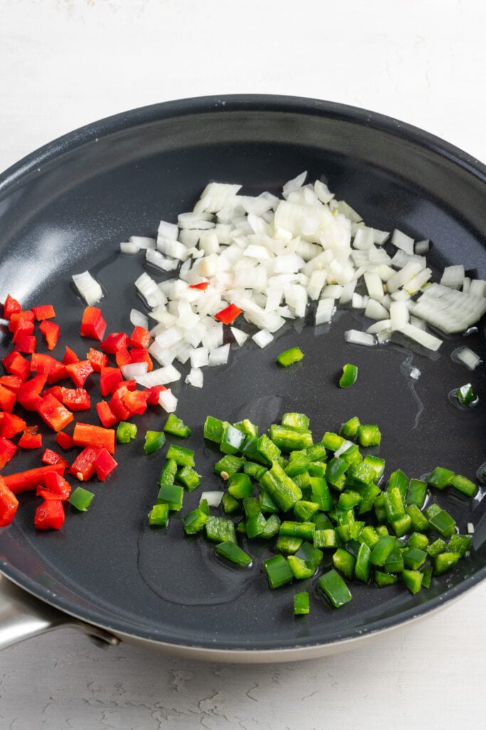 diced bell peppers and onion in a skillet with oil.
