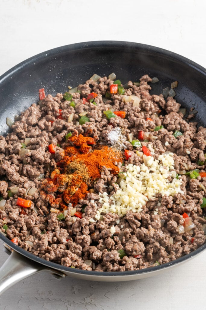 garlic and seasonings added to the skillet with the beef, peppers and onions.