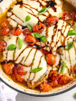 overhead shot of skillet caprese chicken with balsamic glaze, cherry tomatoes, and fresh basil.