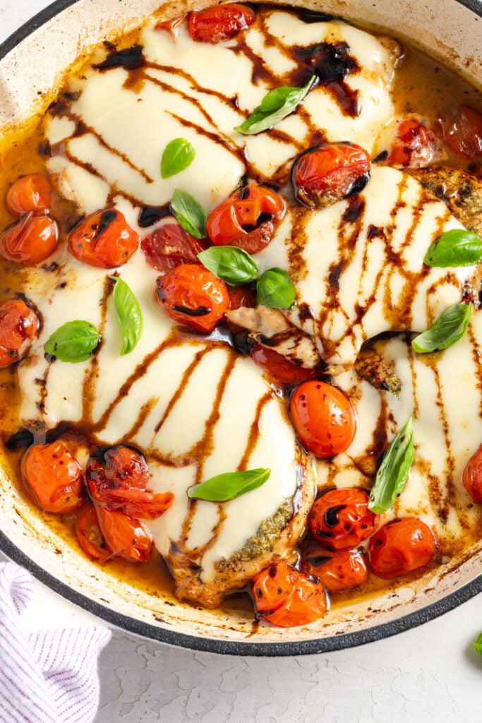 overhead shot of skillet caprese chicken with balsamic glaze, cherry tomatoes, and fresh basil.