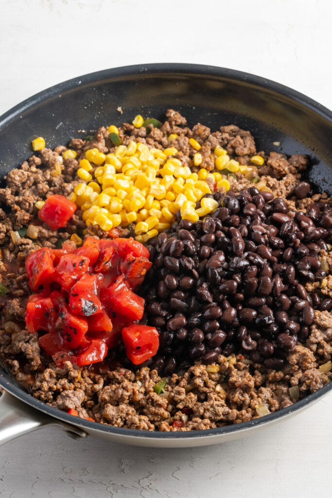 corn, black beans, and fire roasted tomatoes added to the skillet with the seasoned ground beef.