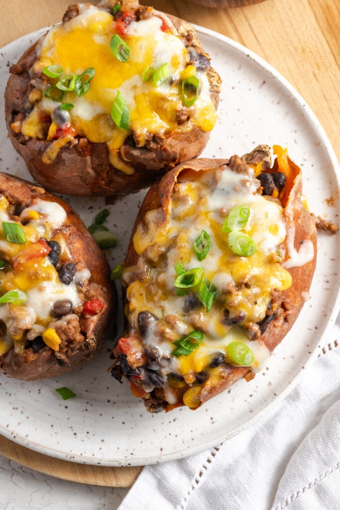 overhead closeup shot of 3 taco stuffed sweet potatoes on a white plate.