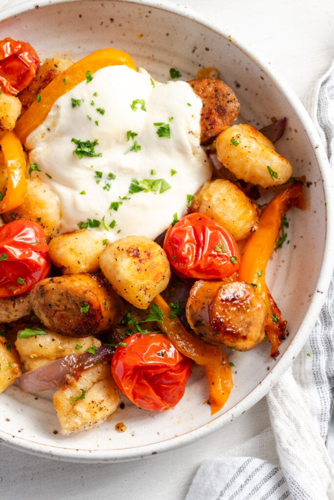 right half of a serving of baked gnocchi sheet pan dinner with chicken sausage and burrata.