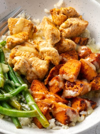 closeup shot of chicken and sweet potato bowl with garlic mojo sauce and green beans.