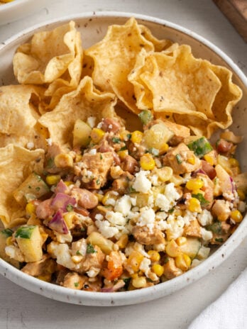 white earthenware pasta bowl filled with high protein chopped salad and tortilla chips for scooping.