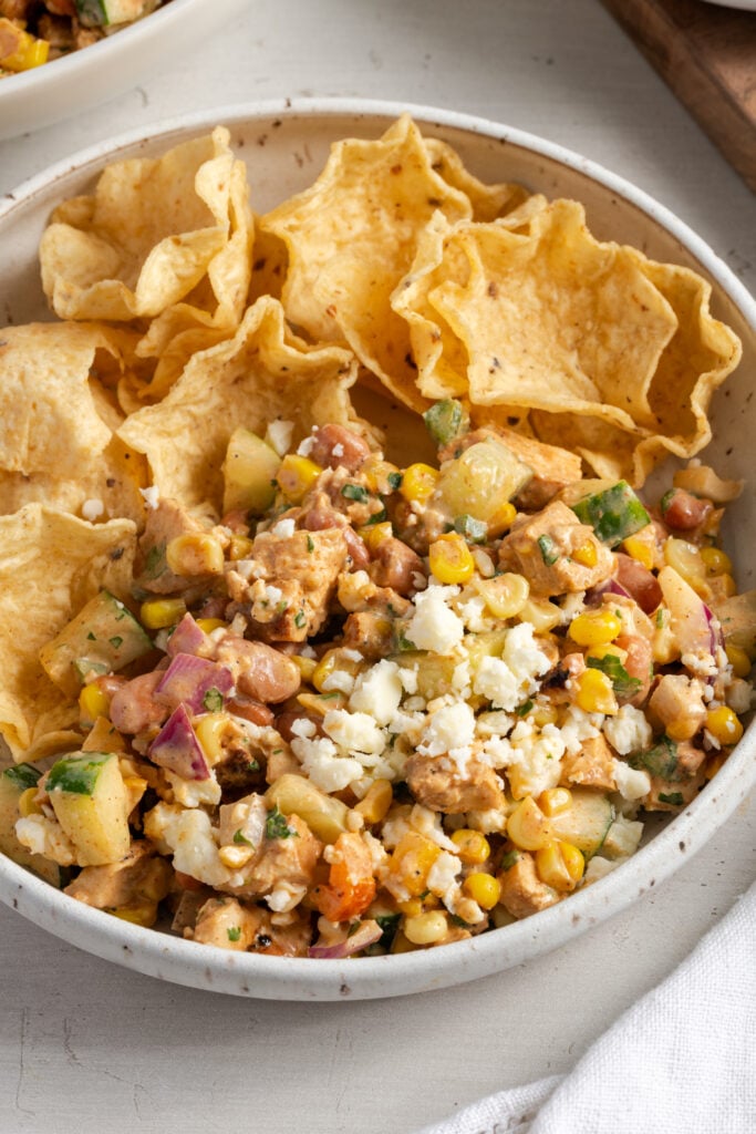 white earthenware pasta bowl filled with high protein chopped salad and tortilla chips for scooping.