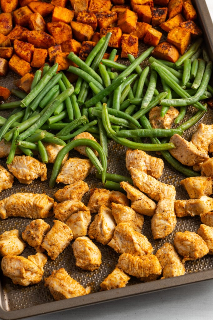chicken, sweet potatoes, and green beans on the sheet pan after baking.