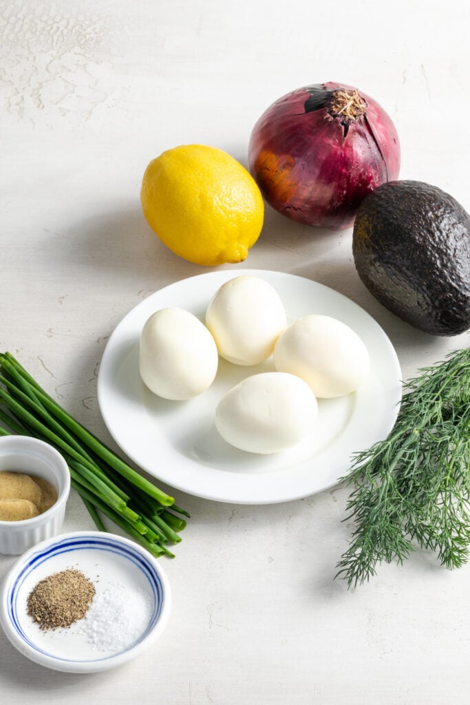 ingredients needed to make avocado egg salad recipe measured out on a white table.