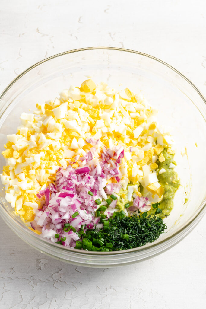 ingredients for avocado & egg salad in a mixing bowl before mixing.