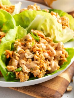 closeup shot of peanut sauce ground turkey lettuce wraps showing the chunky filling, creamy peanut sauce, crunchy chopped peanuts all loaded into butter lettuce wraps.