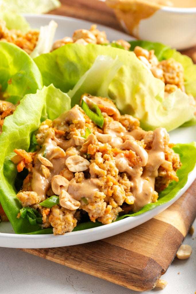 closeup shot of peanut sauce ground turkey lettuce wraps showing the chunky filling, creamy peanut sauce, crunchy chopped peanuts all loaded into butter lettuce wraps.