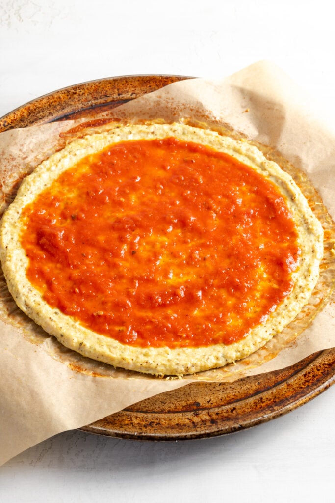 pizza sauce spread on the par-baked chicken pizza crust.