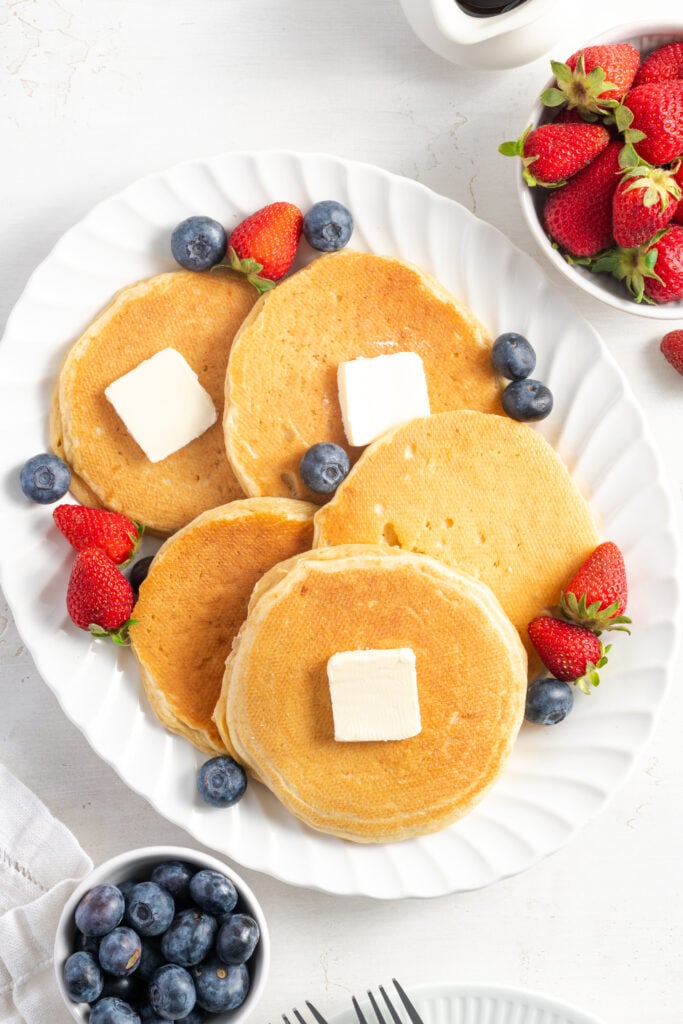 flat lay shot of cottage cheese pancakes with butter and fruit.