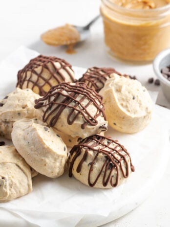 white marble round topped with parchment paper and a pile of greek yogurt frozen peanut butter balls.