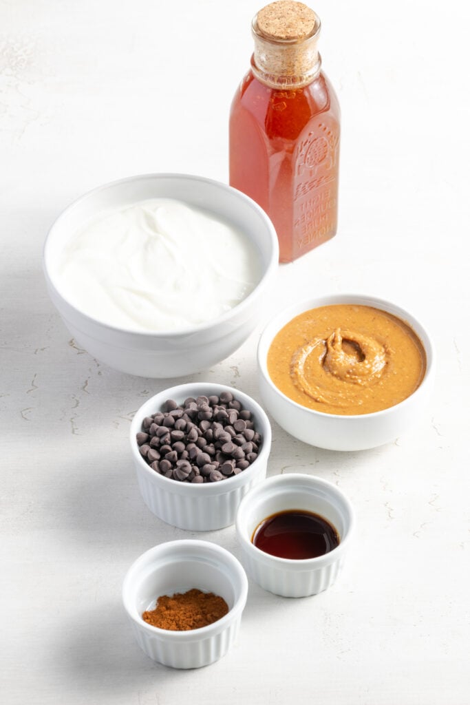 ingredients needed to make healthy peanut butter balls with greek yogurt measured out on a white table.